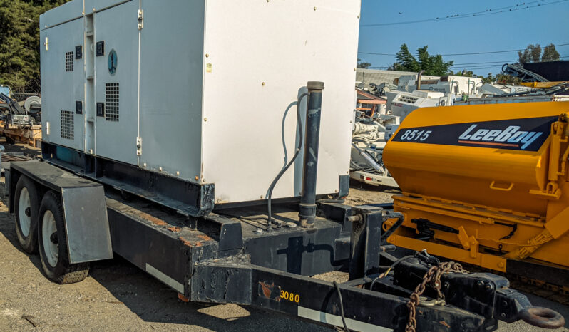 The image shows a towable Multiquip 180KVA generator mounted on a heavy-duty dual-axle trailer. The generator housing is white, with ventilation grilles and latches on the sides for access. The trailer has a black frame and it includes a hitch setup for towing, complete with a chain and heavy-duty hook. In the background, a yellow LeeBoy 8515 machine is visible, along with other industrial equipment. The scene appears to be in an outdoor yard or equipment lot.